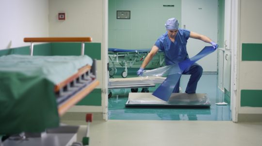 In the picture there is a man in the hospital, peeling off one layer off a decontamination mat.